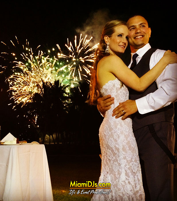 Newlyweds kissing as fireworks go off behind them