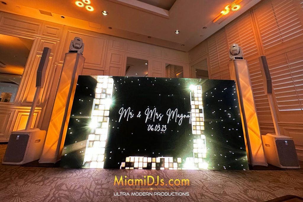 Mr and Mrs on a black LED wall between lit columns in a warm amber ballroom