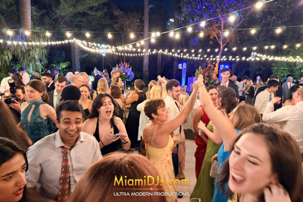 Guests dancing outdoors under string lights at Miami Beach Botanical Garden