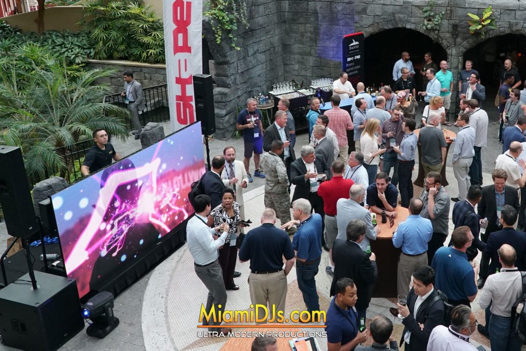 Badged guests networking beside sponsor banners at a conference welcome reception