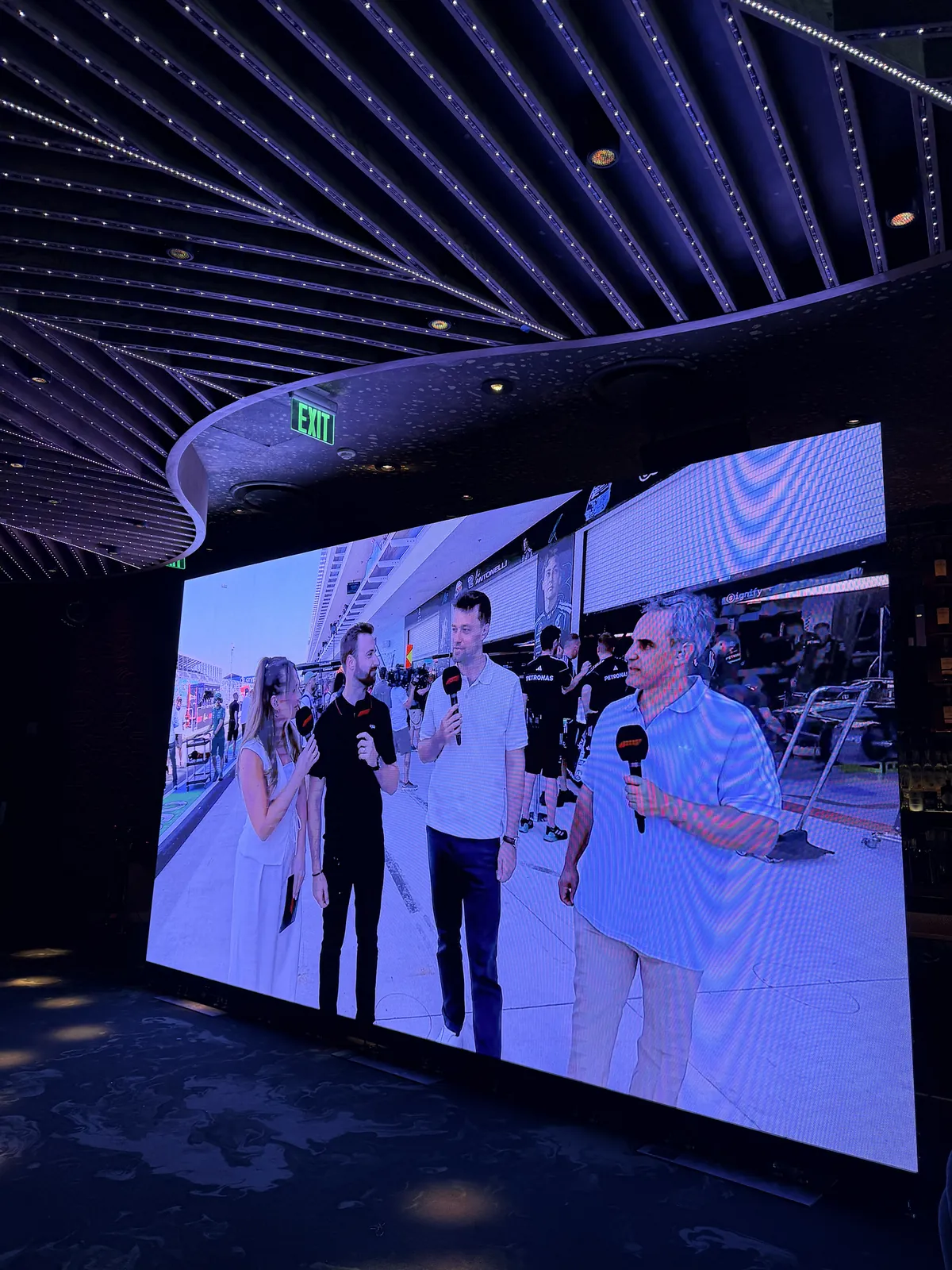 LED video wall showing live F1 Miami pit lane coverage under a lit lounge ceiling, built by Miami DJs